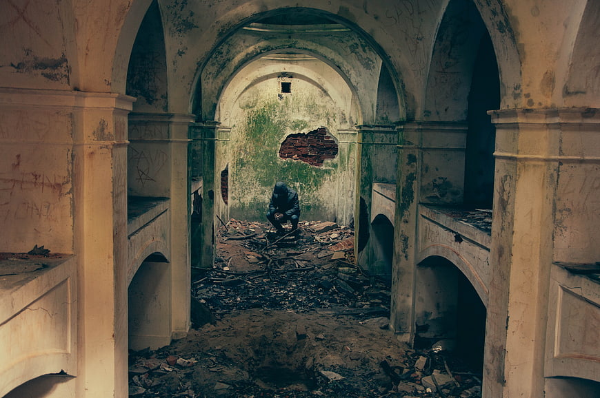 Man sitting in the rubble of a destroyed arched building