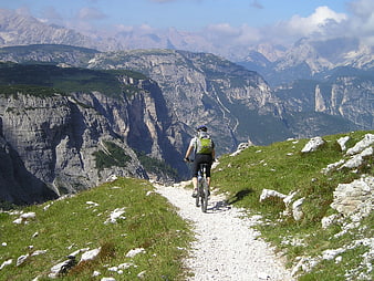 Mountain Biker Riding Gravel Trail Through Dramatic Alpine Landscape