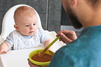 Father Feeding Baby Puree in High Chair