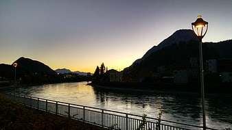 Serene River at Dusk with Glowing Street Lamp and Mountains