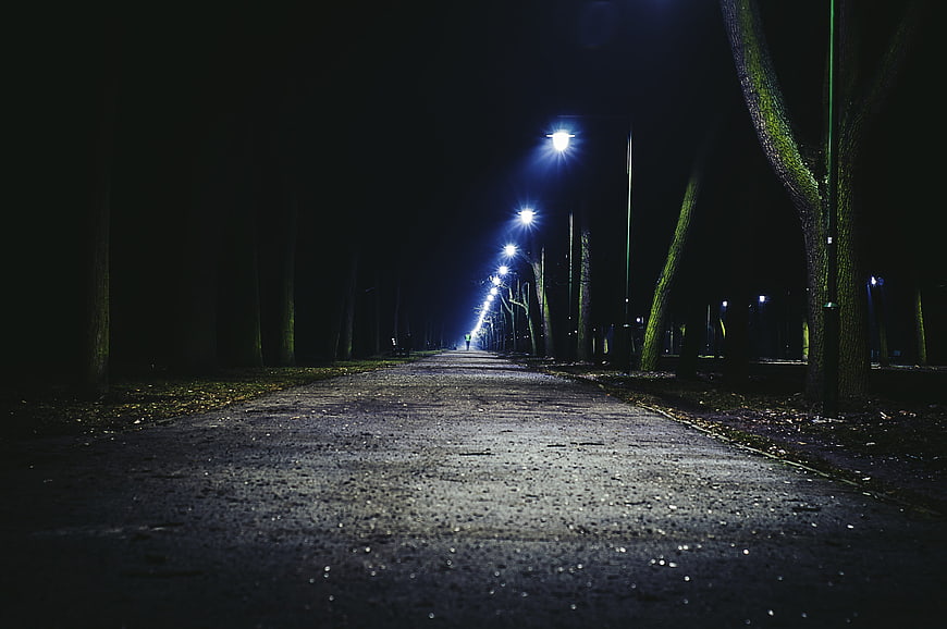 Empty asphalt road at night illuminated by streetlights