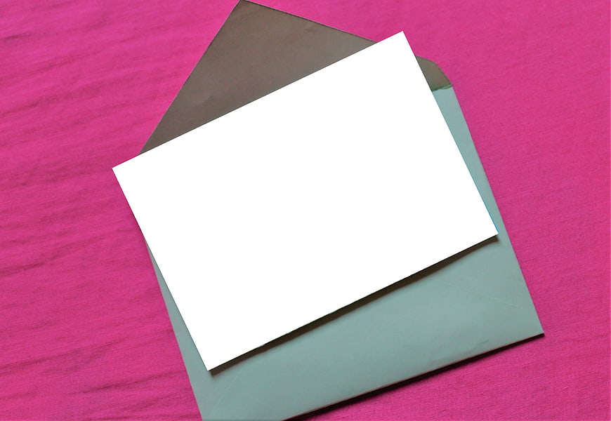 Blank white card and green envelope on pink background