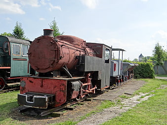 Rusty red vintage steam locomotive on narrow-gauge tracks