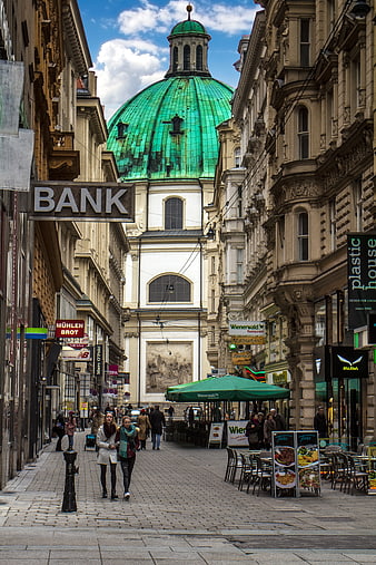 Pedestrians Walking on Cobblestone Street Towards Green Dome