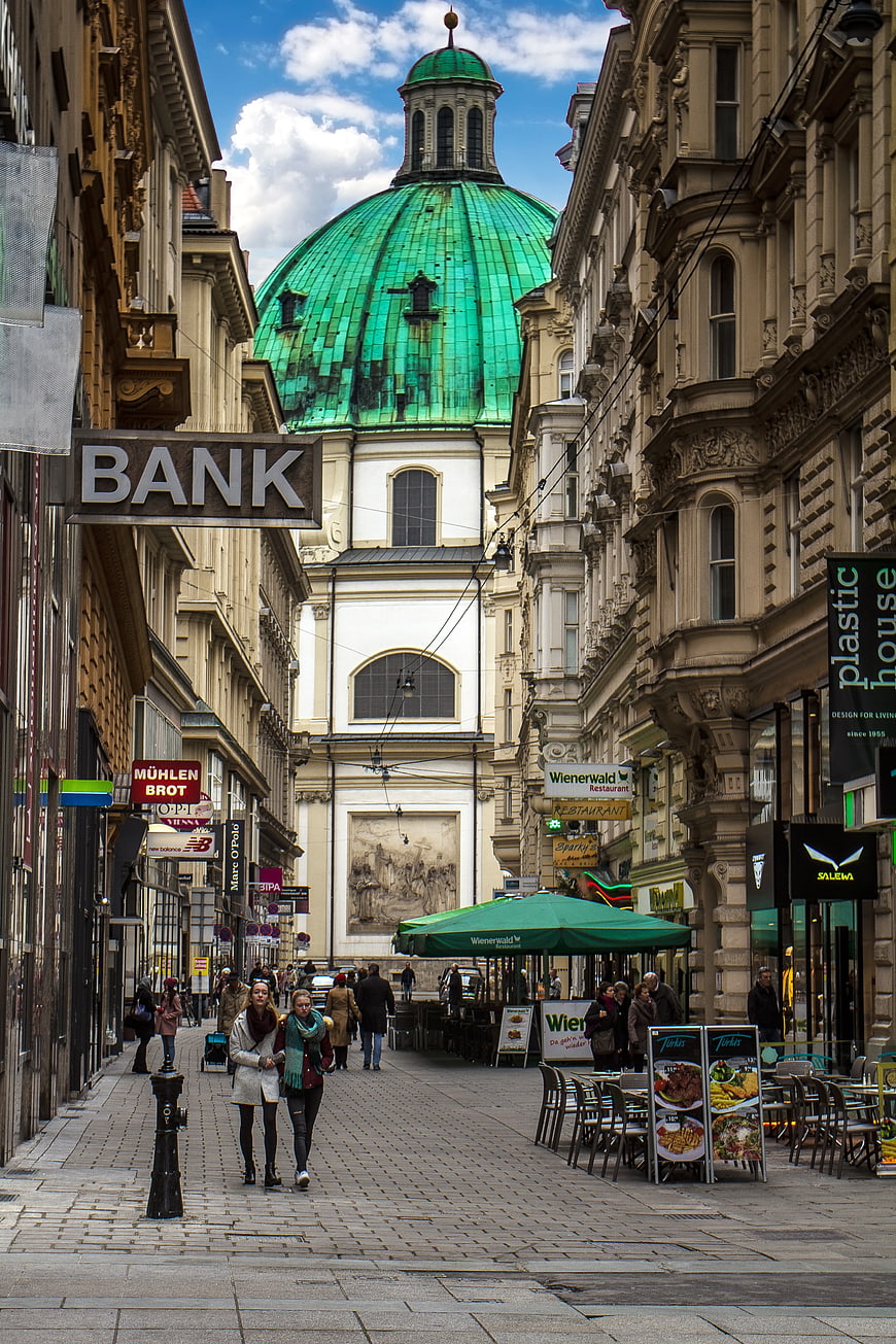 Pedestrians Walking on Cobblestone Street Towards Green Dome