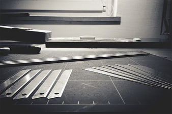 Crafting tools and metal blades on a cutting mat workspace
