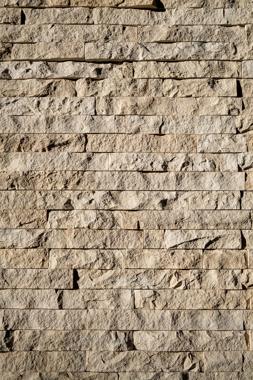 Textured beige stone wall background with horizontal masonry pattern