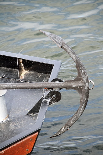 Close-up of weathered boat anchor with spiderwebs on water