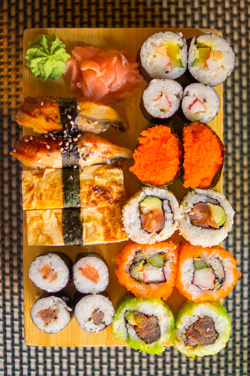 Overhead view of assorted sushi platter on wooden board