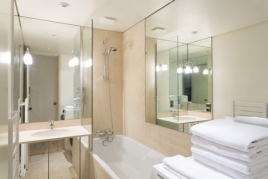 Modern bathroom interior with bathtub, mirror, and white towels