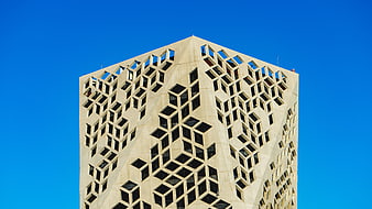 Modern geometric skyscraper facade against blue sky