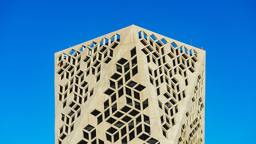 Modern geometric skyscraper facade against blue sky