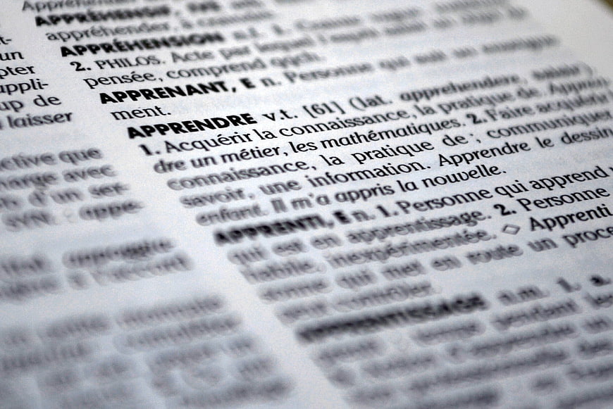 Close-up of French dictionary page defining the word apprendre