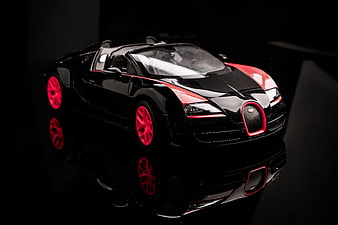 Black and Red Bugatti Veyron Model Car on Reflective Surface