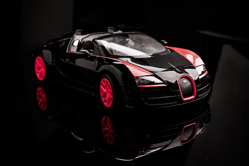 Black and Red Bugatti Veyron Model Car on Reflective Surface