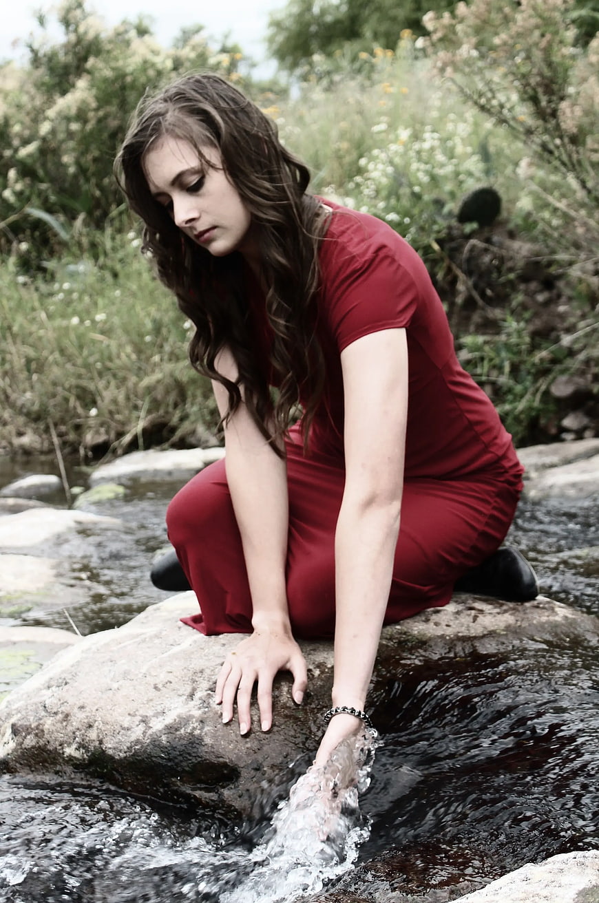 Woman in Red Dress Touching Stream Water