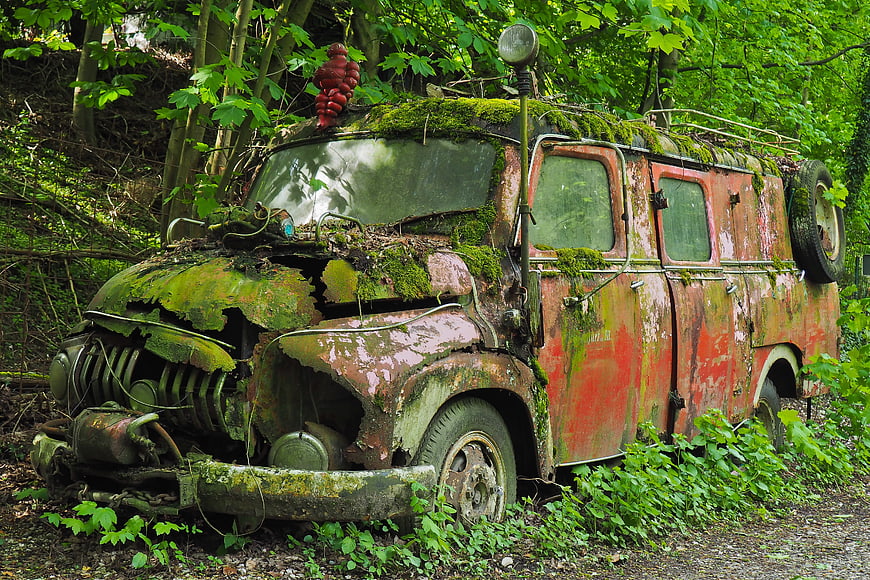 Rusty vintage fire truck abandoned in overgrown forest