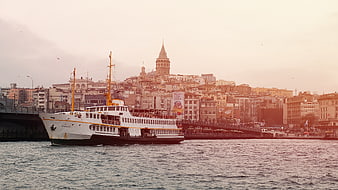 Ferry boat passing Galata Tower in Istanbul at sunset