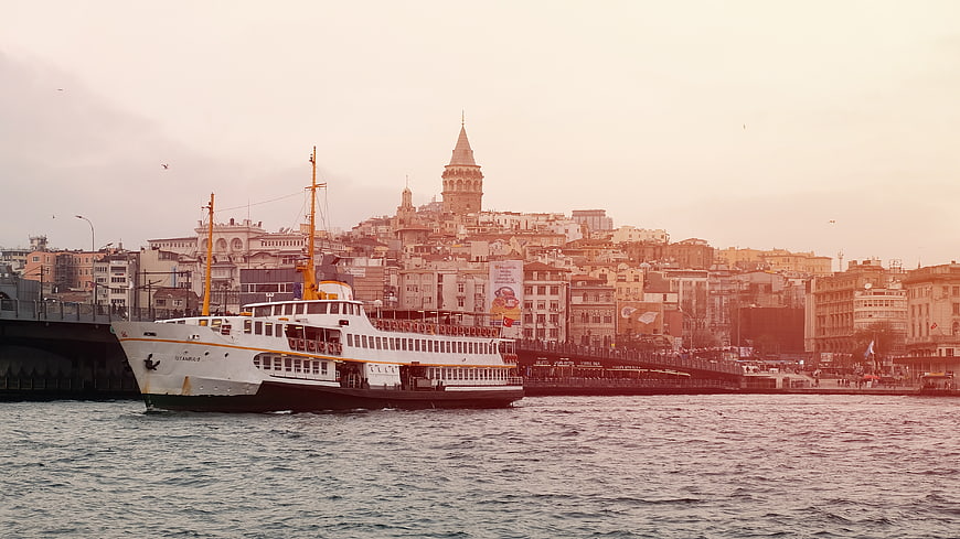 Ferry boat passing Galata Tower in Istanbul at sunset
