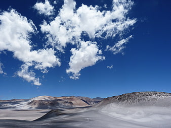 Vast white sand dunes under blue sky with clouds