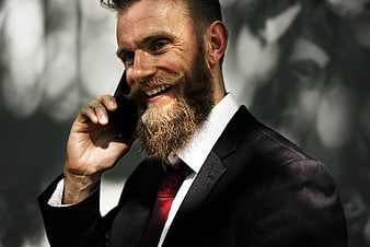 Bearded businessman in suit smiling while talking on mobile phone