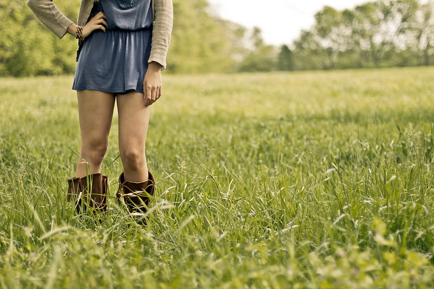 Woman in Brown Boots Standing in Green Grass Field