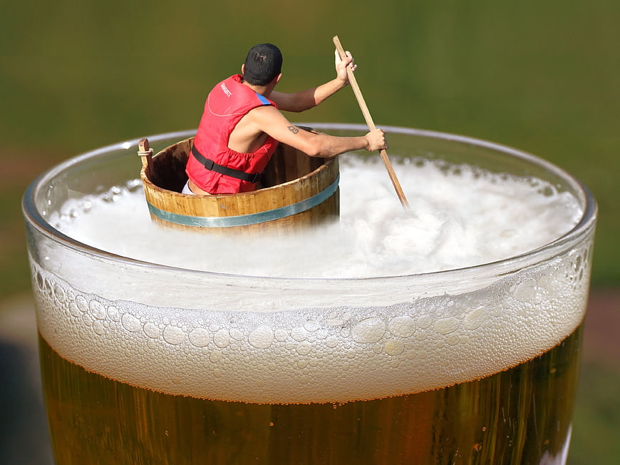 Man rowing barrel boat in giant beer glass