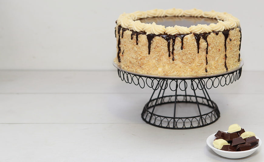 Chocolate Drip Cake With Coconut Crumbs On Black Wire Stand