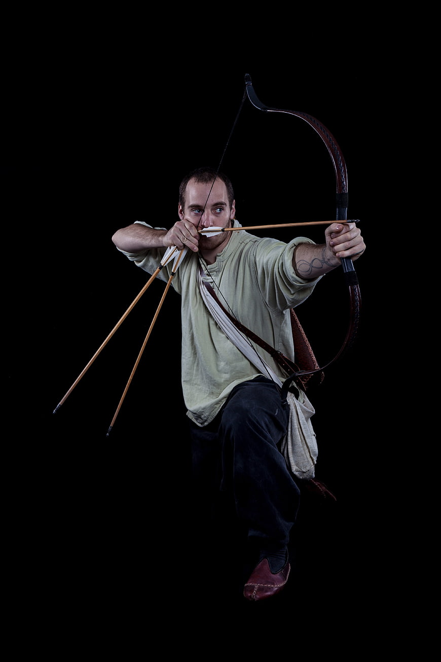 Medieval Archer Drawing Longbow Against Black Background