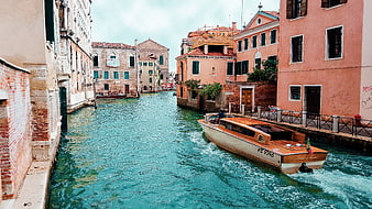 Orange wooden water taxi speeding through Venice canal