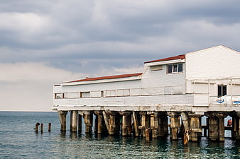 White wooden pier building on concrete pillars over the sea