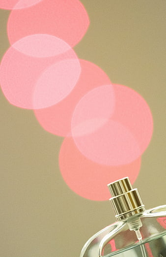 Close-up of perfume bottle with pink bokeh background