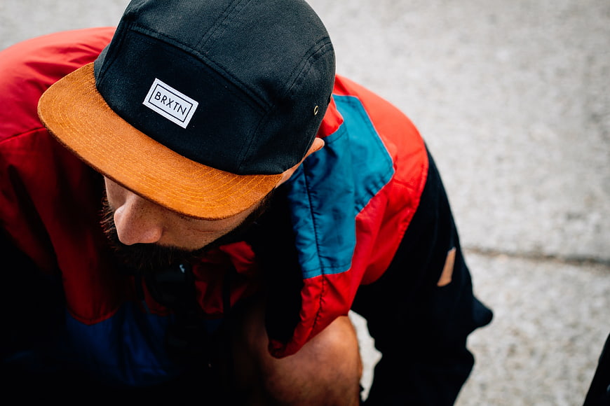 Man in Colorful Jacket and Snapback Cap Looking Down