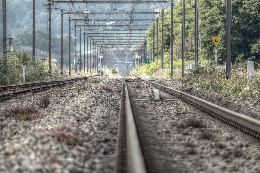 Abandoned Railway Tracks With Catenary Poles And Gravel Ballast