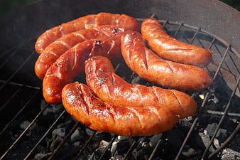 Grilled sausages cooking on charcoal barbecue grill