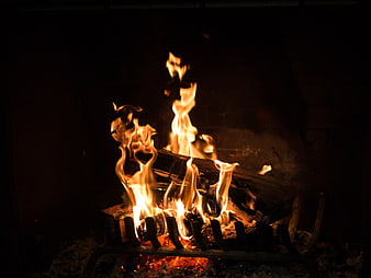 Close-up of burning logs in a dark fireplace
