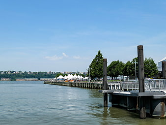 Sunny waterfront pier with white tents and city skyline