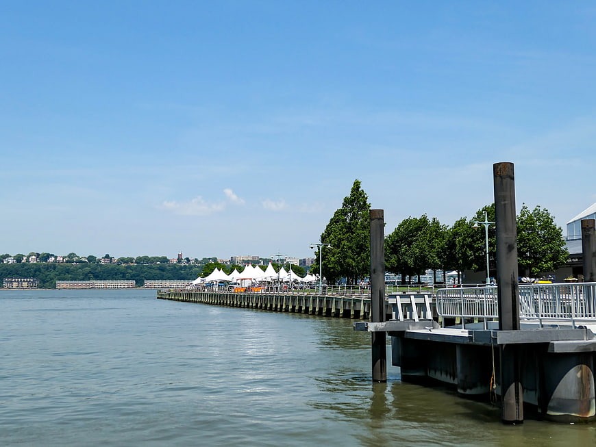 Sunny waterfront pier with white tents and city skyline