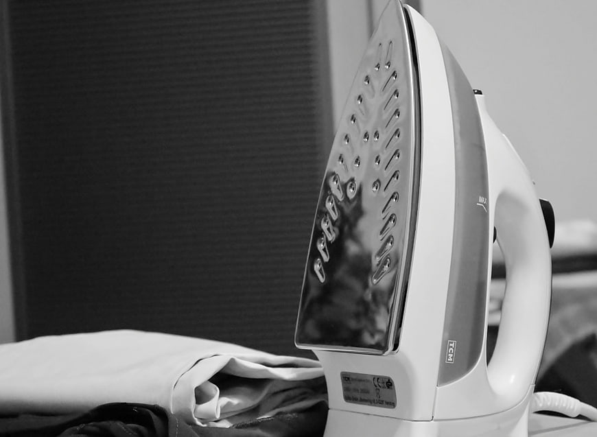 Close-up of white steam iron on clothes