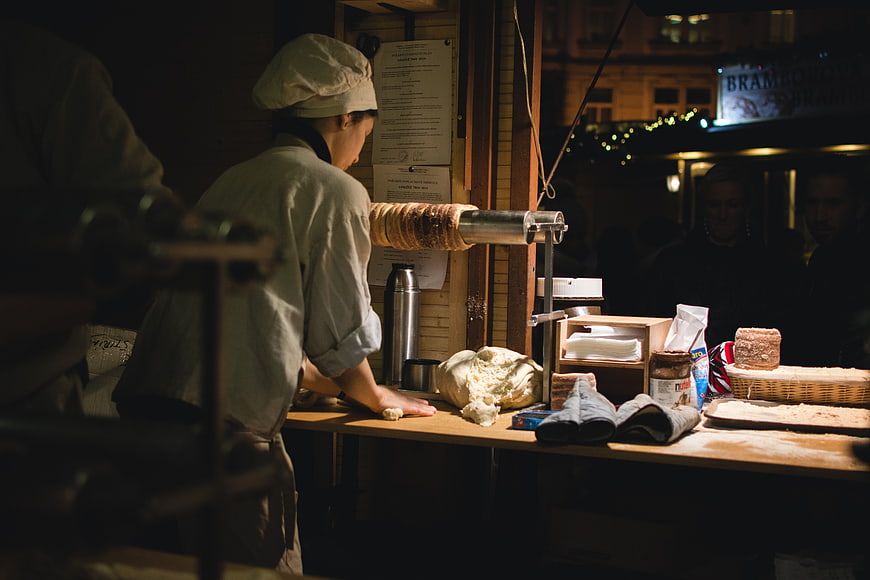Baker preparing traditional Czech Trdelnik pastry at night market