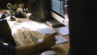 Music Producer Writing Notes at Wooden Desk with Computer