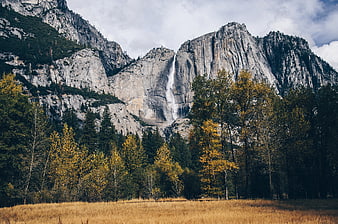 Majestic waterfall cascading down granite cliffs in autumn landscape
