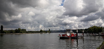 Wide river landscape with dramatic clouds and docked boat