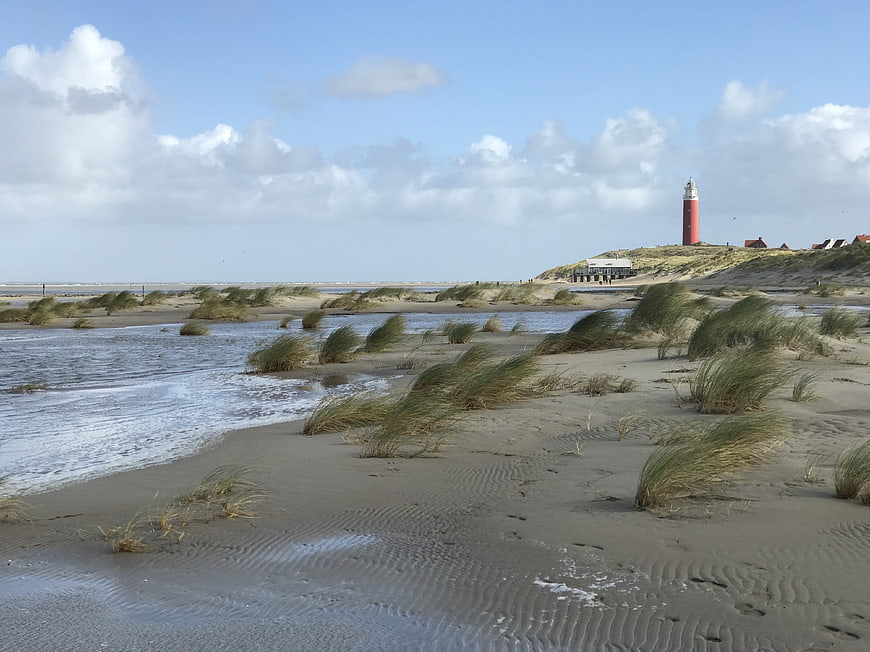 Red Lighthouse on Sandy Dunes with Windblown Grass