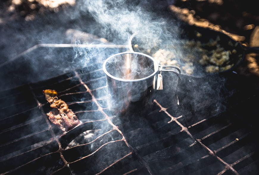 Smoky Campfire Cooking with Metal Mug and Bacon