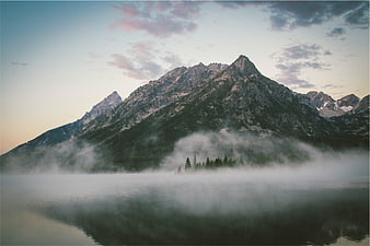 Misty mountain landscape with lake reflection at dawn