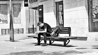 Man sitting on bench looking at smartphone in black and white