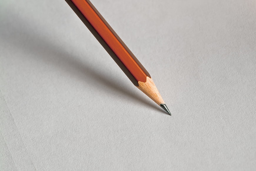 Close-up of a sharpened orange pencil on white paper