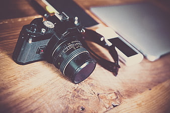 Vintage SLR Camera on Wooden Desk with Laptop and Smartphone