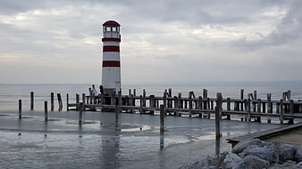 Red and white lighthouse on frozen pier in winter
